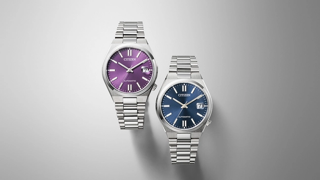 Citizen Tsuyosa 37, Referenz NJ0200-50W und NJ0200-50M, zwei Uhren mit blauem und violettem Zifferblatt vor grauem Hintergrund