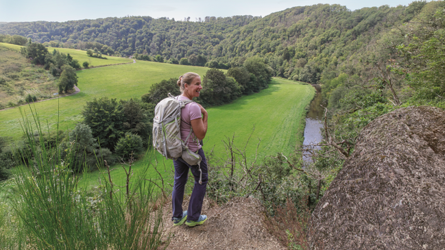 Die Autorin auf einem Wanderweg vor einem Ausblick auf einen Wald