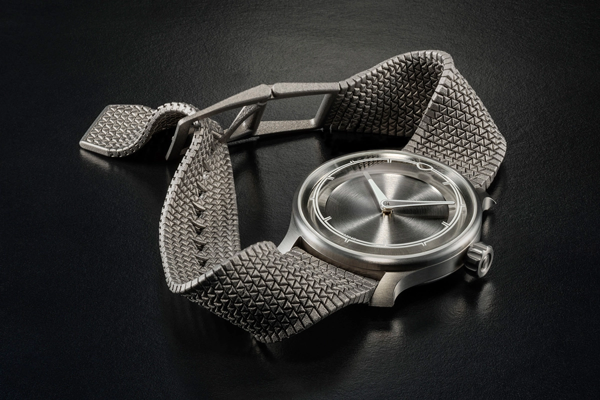 Ming-Polymesh mit Uhr, liegend vor grauem Hintergrund