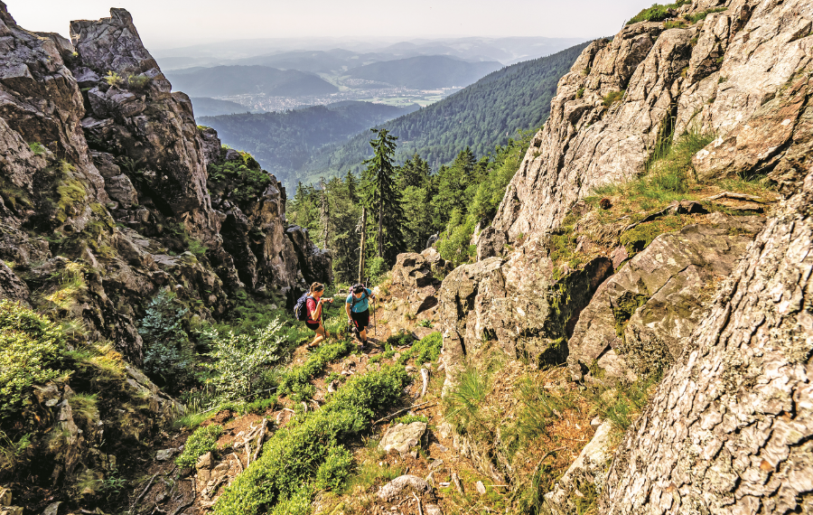 Zwei Wanderer laufen zwischen großen Felsformationen einen Berg hinauf