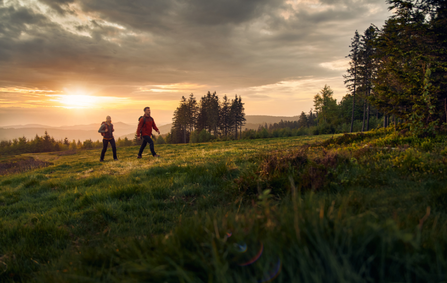 Zwei Wanderer auf einem Wanderweg auf der Wiese beim Sonnenuntergang