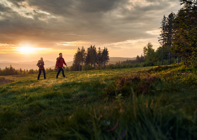 Zwei Wanderer auf einem Wanderweg auf der Wiese beim Sonnenuntergang