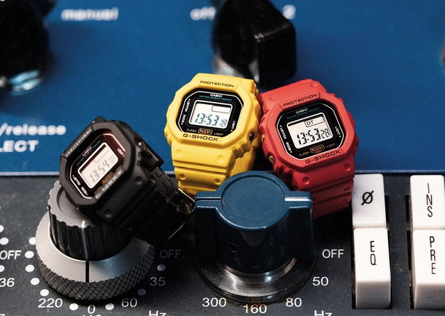 G-Shock DWN-5600 Uhr im Ringformat, drei Modelle vor Stereoanlage