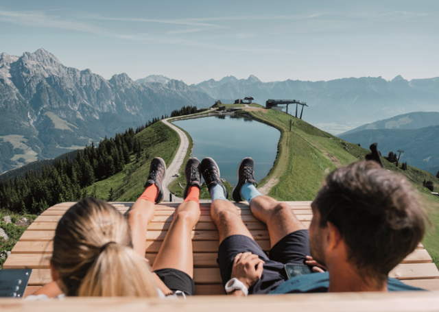Zwei Personen sitzen auf einer Bank und genießen ein Bergpanorama
