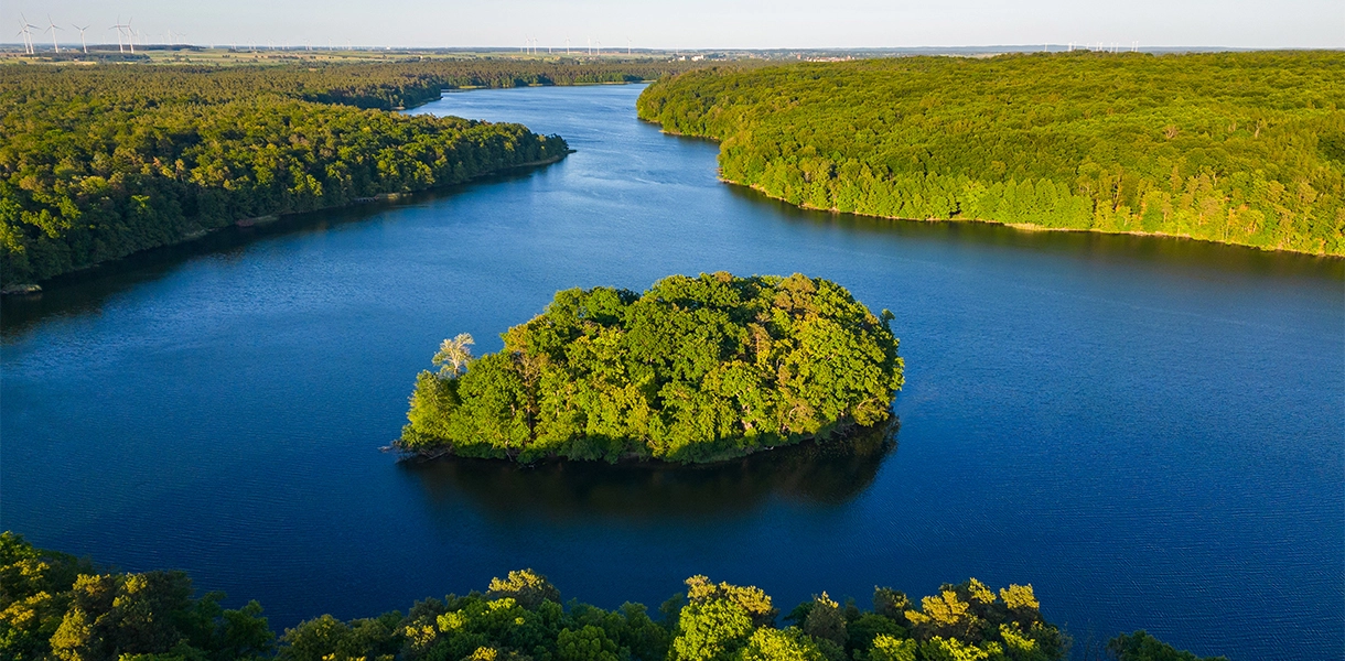 Inspirationen_Wolletzsee_Hero_C-OliverGerhard Landschaftsaufnahme von Wald und einem Gewässer.