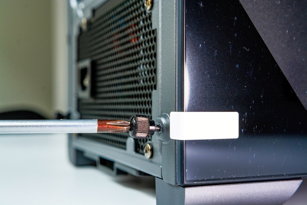 Schraube an Gehäuseseite wird mit Schraubenzieher entfernt