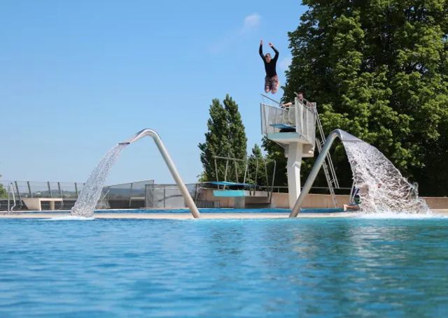 Person springt in Freibad von Sprungturm