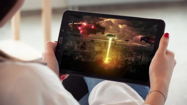 Frau hält Tablet, auf dem ein Actionfilm zu sehen ist