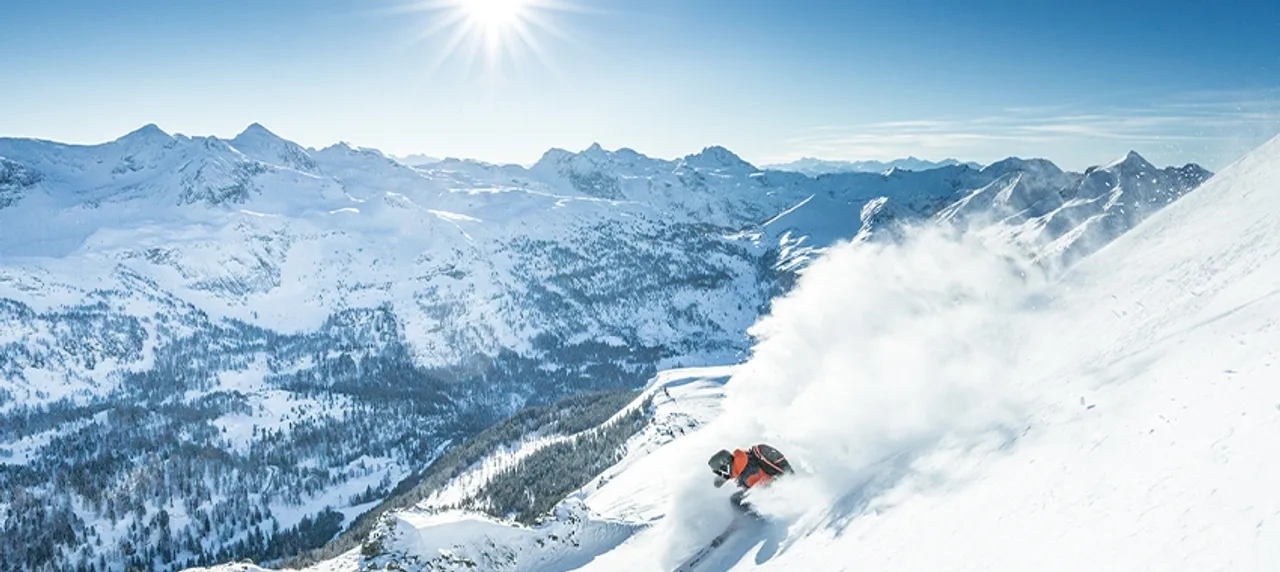 Skifahrer vor verschneiter Bergkulisse in Obertauern bei Sonnenschein.