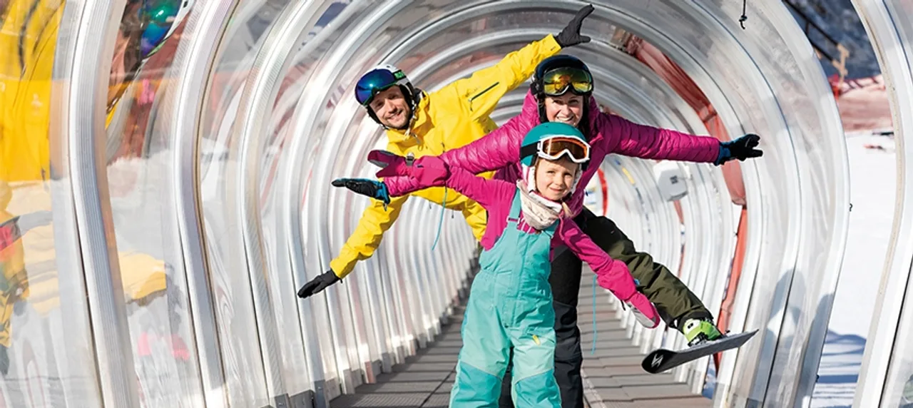Drei Personen mit Ski bei Auffahrt mit Zauberteppich in der Region Seefeld.