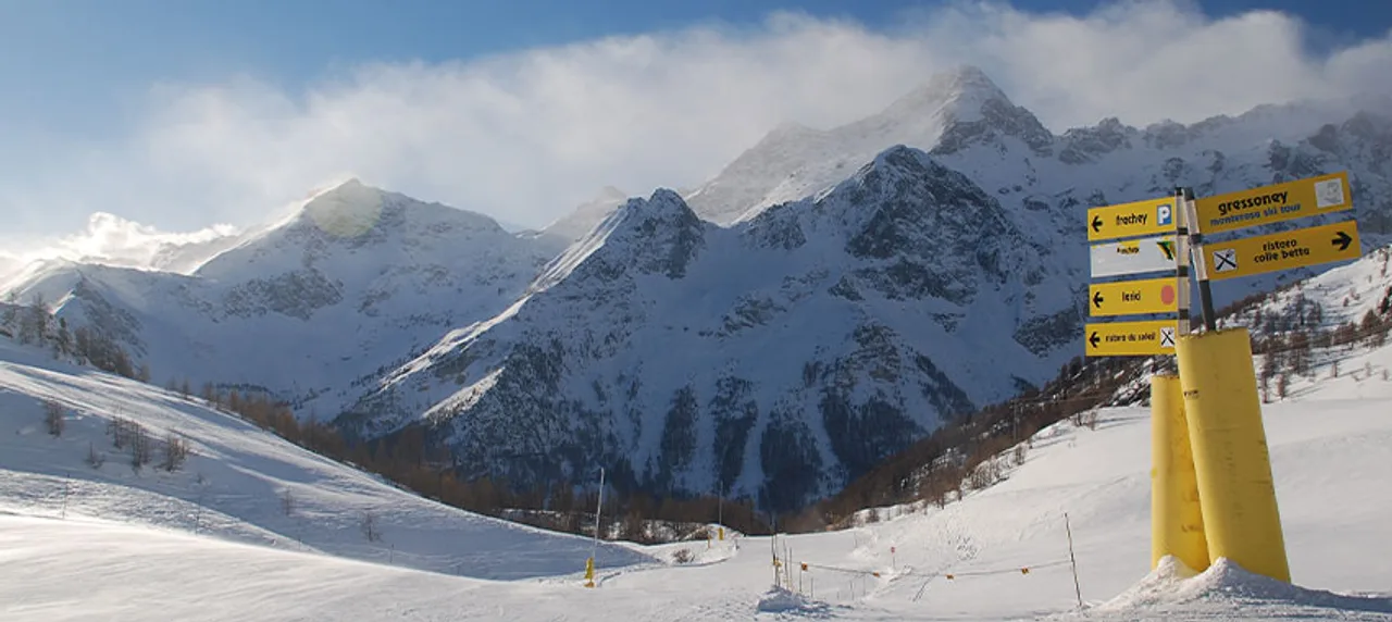 Aufnahme aus dem Skigebiet mit Wegweisern vor schneebedeckten Bergen im Aostatal.