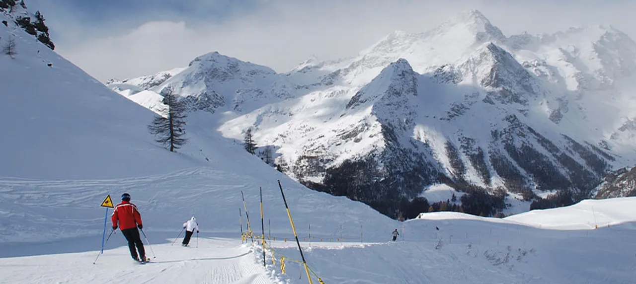 Skifahrer auf der Piste vor verschneiten Bergen im Aostatal.
