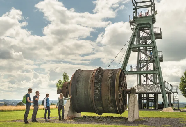 Eine Gruppe steht neben einem Förderturm 