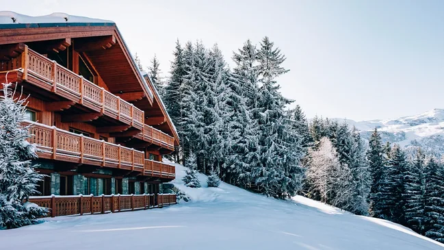 Außenansicht eines Chalets im Winter neben verschneiten Bäumen.