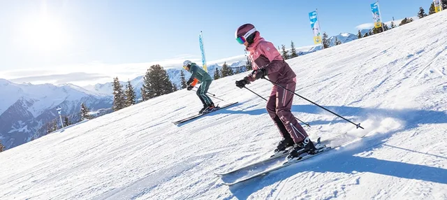 Zwei Skifahrer auf der Piste in Mountopolis.