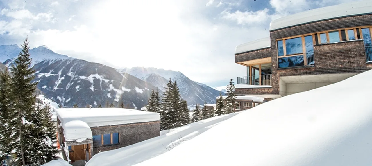 Chalet Deluxe im Gradonna Mountain Resort in Kals am Großglockner neben verschneiter Bergkulisse.