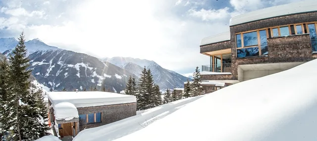 Chalet Deluxe im Gradonna Mountain Resort in Kals am Großglockner neben verschneiter Bergkulisse.