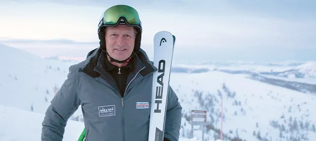 Franz Klammer vor verschneiter Bergkulisse.