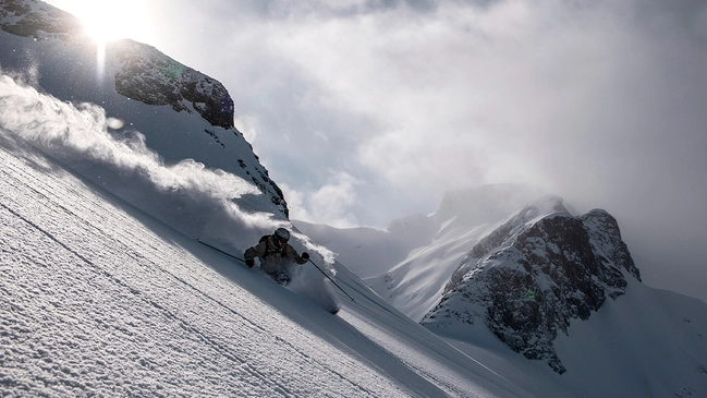 Skifahrer bei Abfahrt durch Tiefschnee in Kanada.