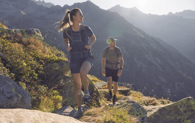 Mehrere Wanderer gehen bergauf in einem lichten, sandigen Kiefernwald