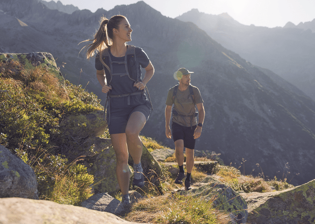 Mehrere Wanderer gehen bergauf in einem lichten, sandigen Kiefernwald