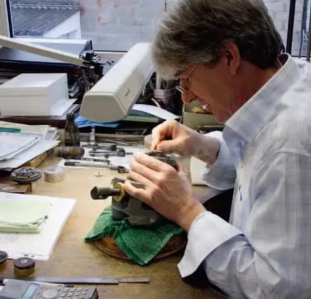 Auf einem Holzstock fixiert, bekommen Teile des Uhrwerks und des Gehäuses ihre Gravur. Den Schriftzug auf letzteren schneidet Jochen Benzinger frei Hand