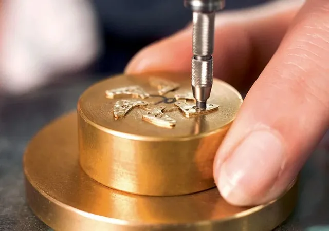 Beim Perlieren der Ankerkloben wird ein diamantgebundener, rotierender Gummistift von Hand kreisförmig über die Oberfläche der Werkteile bewegt.