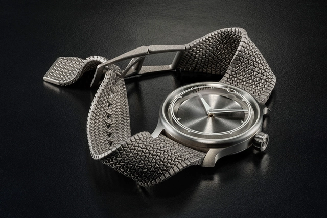 Ming-Polymesh mit Uhr, liegend vor grauem Hintergrund