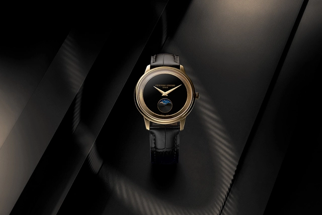 Frederique Constant Classics Moneta Moonphase, Schwarze Uhr mit goldfarbenem Gehäuse vor dunklem Hintergrund