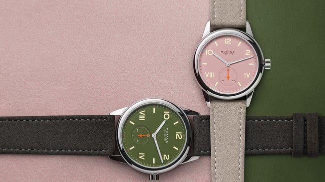Nomos Club Campus in All Olive und Full Rose, zwei Uhren überlappend mit Hintergrund in Grün und Rosa